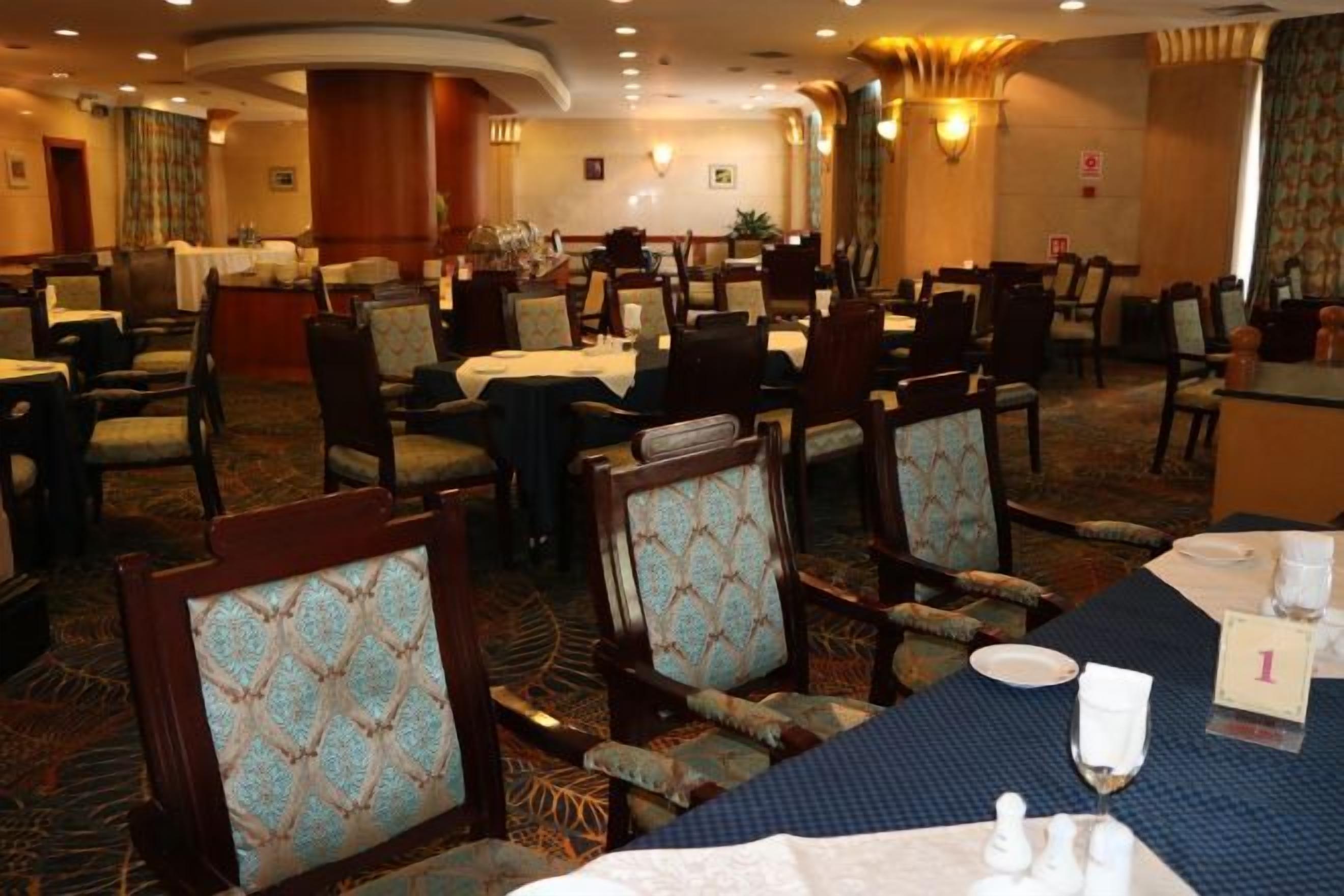 A hotel dining area with multiple tables and chairs, some with table settings.