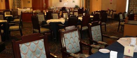 A hotel dining area with multiple tables and chairs, some with table settings.