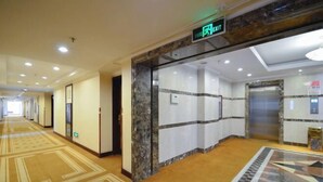 A hotel corridor with a carpeted floor, marble walls, and an elevator. - L. Road Grand Hotel (Lincang)