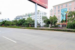 A wide street with buildings, trees, and a clear sky.