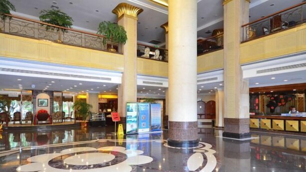 A spacious lobby with a polished marble floor, large columns, and a second-floor balcony with seating. - L. Road Grand Hotel (Lincang)