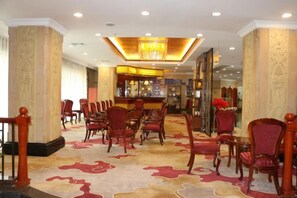 A hotel lobby with a bar area, multiple seating arrangements, and a patterned carpet. - L. Road Grand Hotel (Lincang)