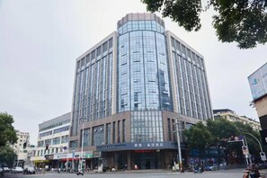 A multi-story building with a modern glass facade, located at a street intersection.