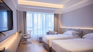A modern hotel room with two beds, a desk with a chair, and a large window with curtains. - Crown Hotel Junyue (Fuzhou)