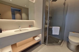 Un baño moderno con ducha de vidrio, lavamanos blanco y retrete.