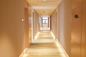 A hotel hallway with a carpeted floor, doors on both sides, and a light source at the end. - Crown Hotel Junyue (Fuzhou)