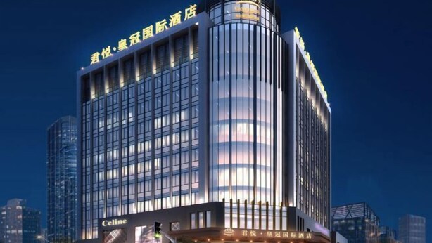 A modern hotel building with a prominent sign at the top and a large advertisement for Celine on the lower level. - Crown Hotel Junyue (Fuzhou)
