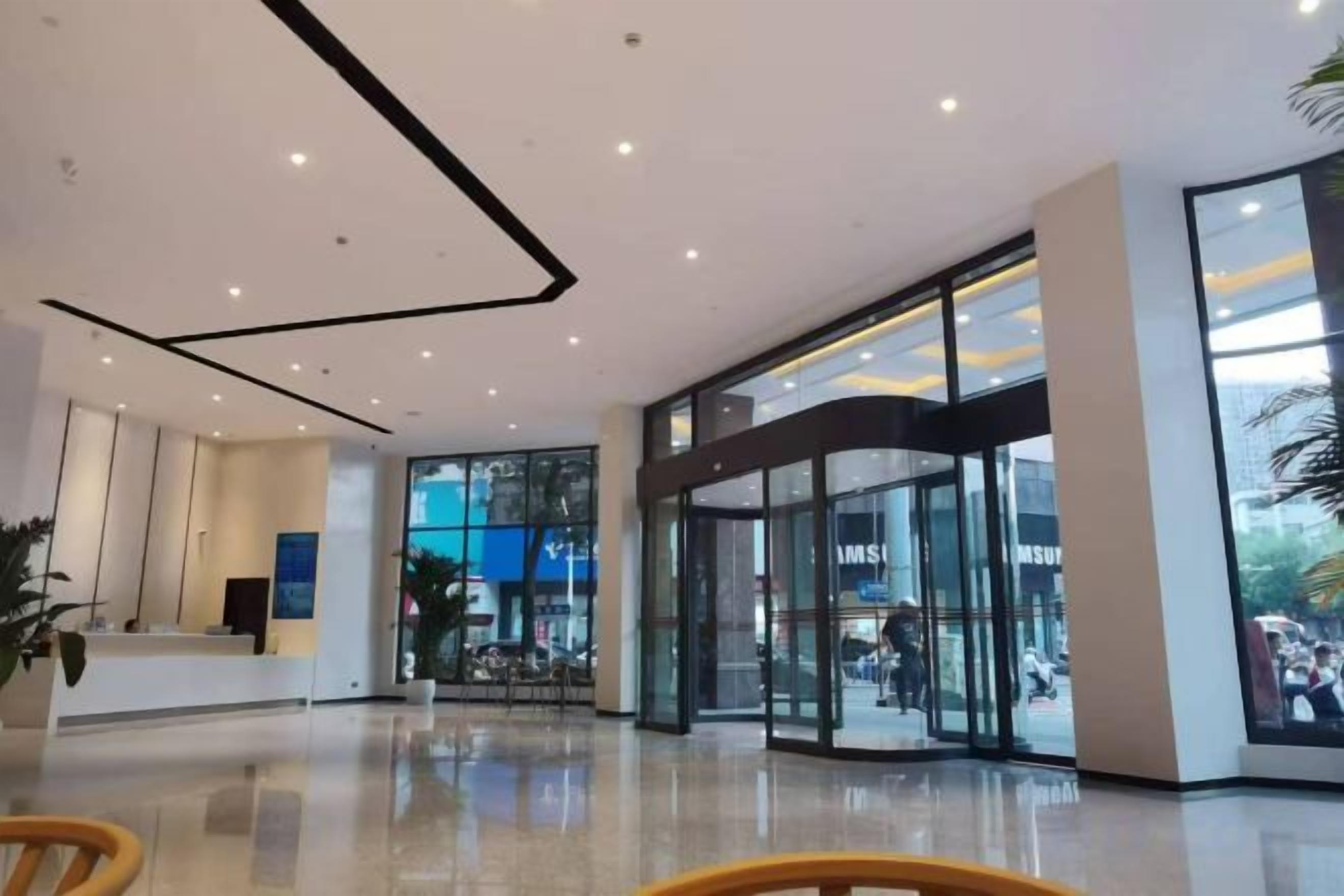 Un interior moderno con una mesa de recepción, puertas de vidrio y un suelo limpio y brillante.
