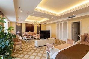 A hotel room with a large bed, a TV, a sofa, a coffee table, and a chandelier. - Changtai Palace Hotel (Hanggin Banner)
