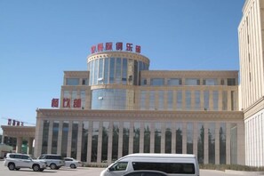 A multi-story building with a cylindrical section and a large glass facade. - Changtai Palace Hotel (Hanggin Banner)