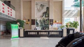 A reception area with a traditional Chinese mural, a reception desk, and a massage chair. - Changtai Palace Hotel (Hanggin Banner)