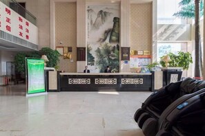 Ett välkomstområde med en traditionell kinesisk väggmålning, en receptionsdisk och en massagestol.