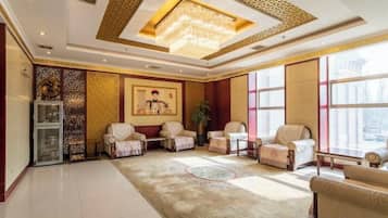A spacious lobby with a chandelier, seating area, and large windows.