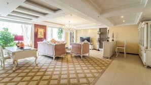 A hotel room with a patterned carpet, a sofa, a television, and a cabinet.