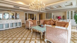 A spacious room with ornate furniture, a chandelier, and a patterned floor.