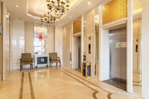 A hotel lobby with a marble floor, two armchairs, a chandelier, and an elevator. - Changtai Palace Hotel (Hanggin Banner)