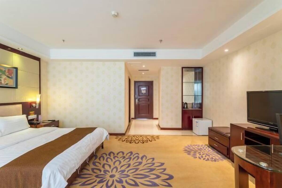 Una habitación de hotel con cama, televisión, escritorio y baño.