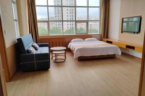 A hotel room with a bed, a sofa, a small round table, and a TV mounted on the wall. - Yujia Hotel (Rongcheng Sakura Lake Sports Park) (Rongcheng)