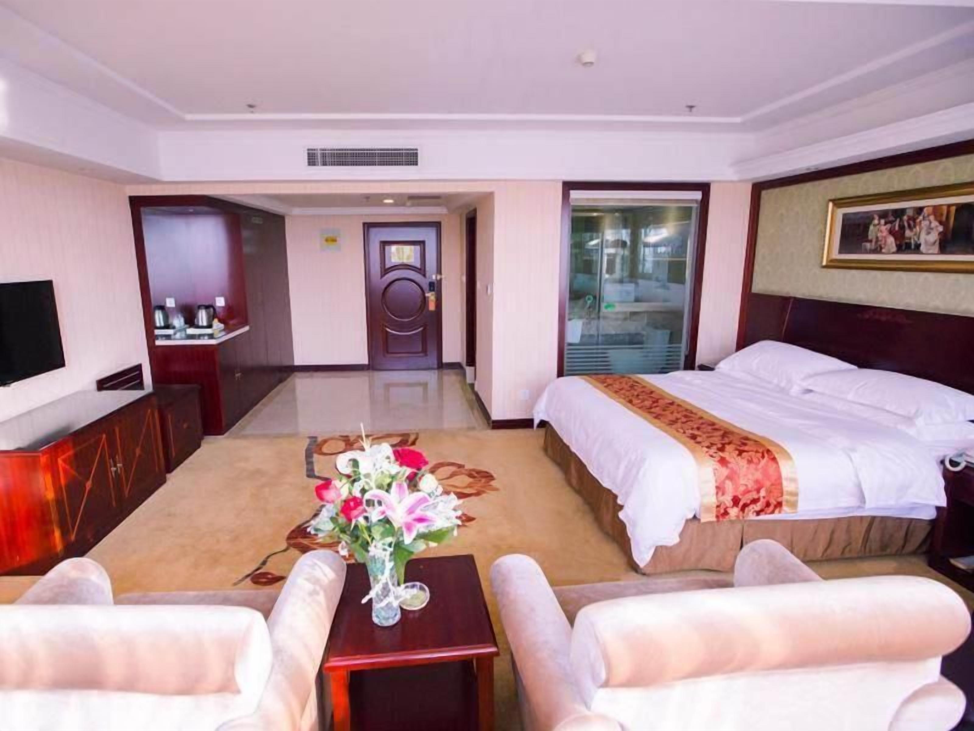 Una habitación de hotel con cama, televisión, escritorio y silla.