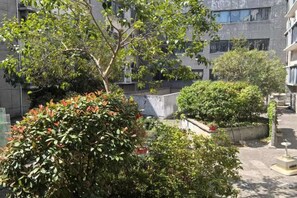A courtyard with trees and a building in the background. - Vienna International Hotel (He Yuan Store, Outlets Plaza, Yangzhou) (Yangzhou)