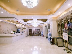A hotel lobby with a reception desk, a chandelier, and a seating area. - Vienna International Hotel (Yangzhou)