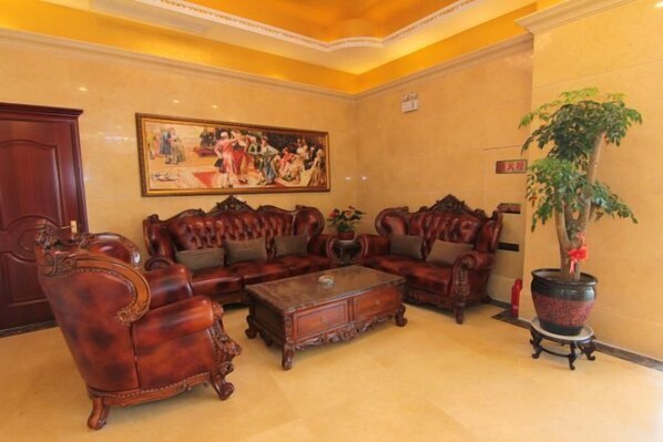 A traditional room with a large sofa set, a coffee table, and a painting on the wall. - Vienna International Hotel (He Yuan Store, Outlets Plaza, Yangzhou) (Yangzhou)