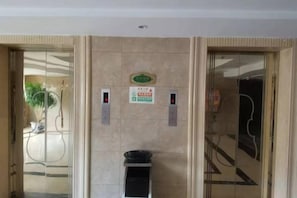A hotel lobby with a reception desk, a plant, and a wall-mounted sign. - Vienna International Hotel (He Yuan Store, Outlets Plaza, Yangzhou) (Yangzhou)