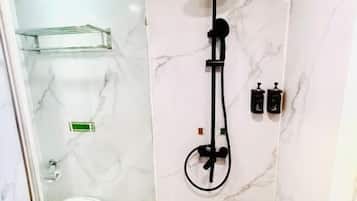 A bathroom with a glass shower enclosure, a toilet, and a marble wall.