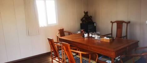 Un comedor con una mesa y sillas de madera, una ventana con cortinas y una chimenea.