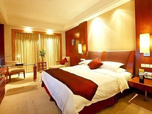 Quarto de hotel com uma cama grande, uma escrivaninha e uma cadeira.