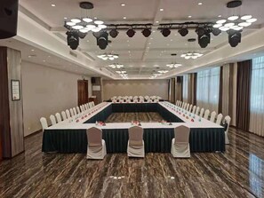 A conference room with a long table, chairs, and a stage with lighting. - Xin Ci Hotel (Yancheng)