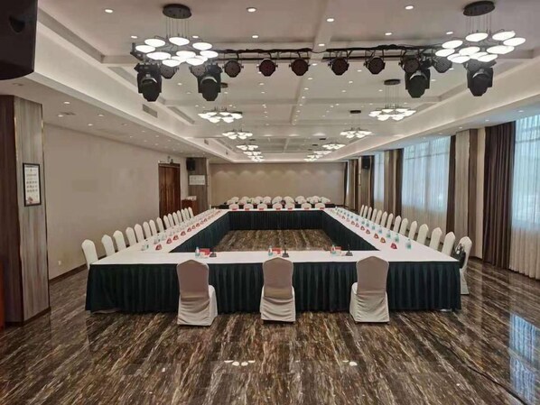 A conference room with a long table, chairs, and a stage with lighting.