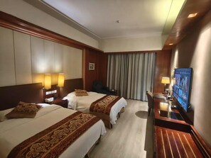 A hotel room with two beds, a desk with a computer, and a television.