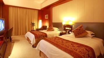 A hotel room with two beds, a television, a desk, and a lamp.
