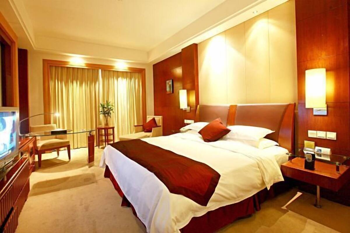 A hotel room with a large bed, a TV, a desk, and a chair.