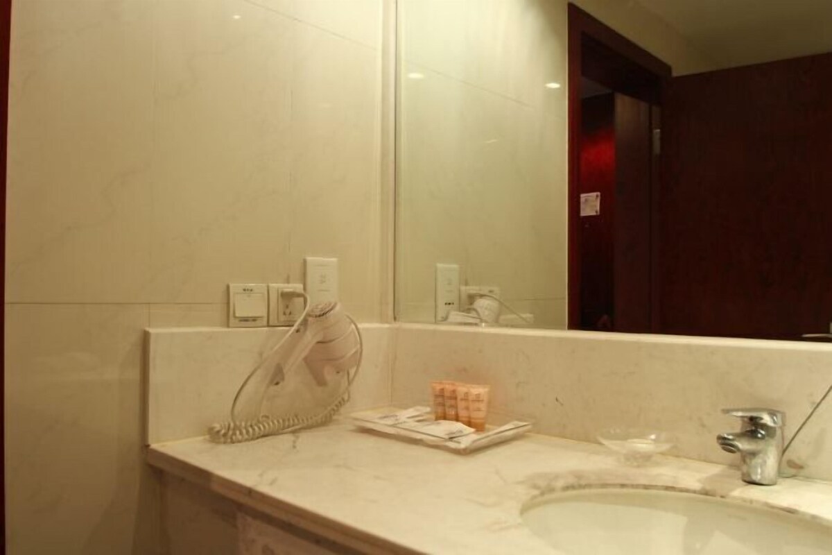 A bathroom with a mirror, a sink, a telephone, and toiletries on the counter.