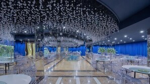A spacious banquet hall with a checkered floor, clear plastic chairs, and tables. - Fan Chang Hotel (Wuhu)