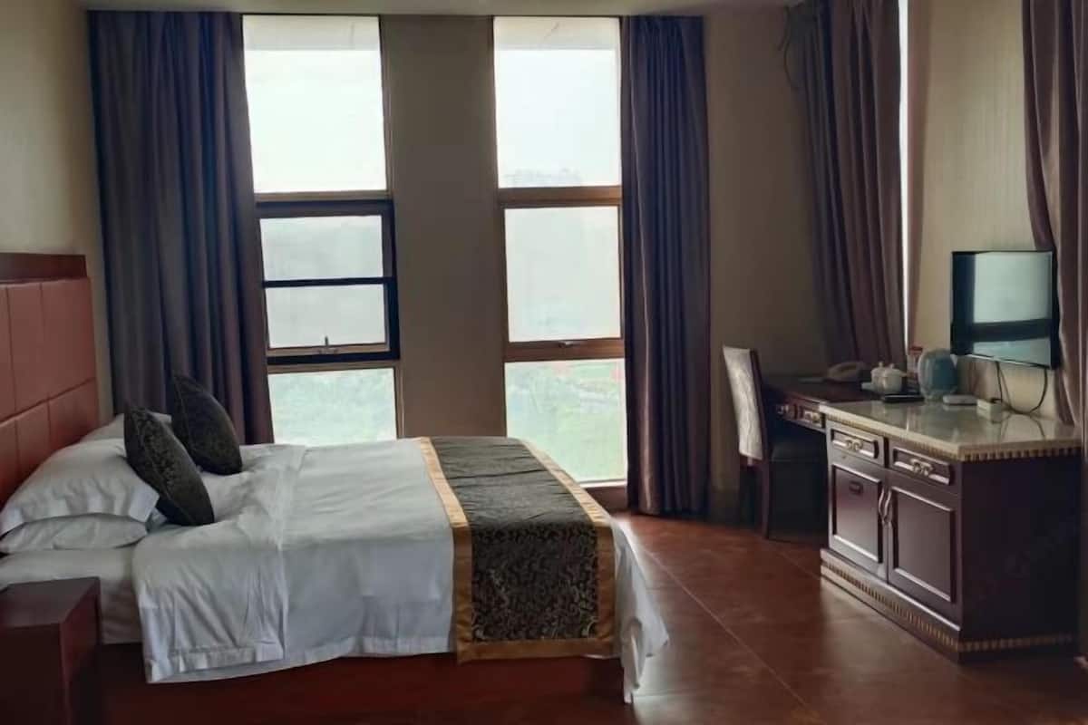 A hotel room with a bed, a desk, and a television.