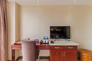 A hotel room with a desk, a television, a cushioned bench, and a minibar. - Fan Chang Hotel (Wuhu)