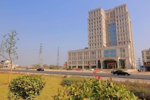 A multi-story building with a large entrance and a parking lot in front. - Fan Chang Hotel (Wuhu)