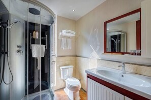 A bathroom with a glass shower enclosure, a white toilet, a sink with a mirror, and a towel rack. - Fan Chang Hotel (Wuhu)