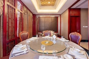 Uma sala de conferência com uma mesa de vidro redonda, cadeiras e uma tela grande.