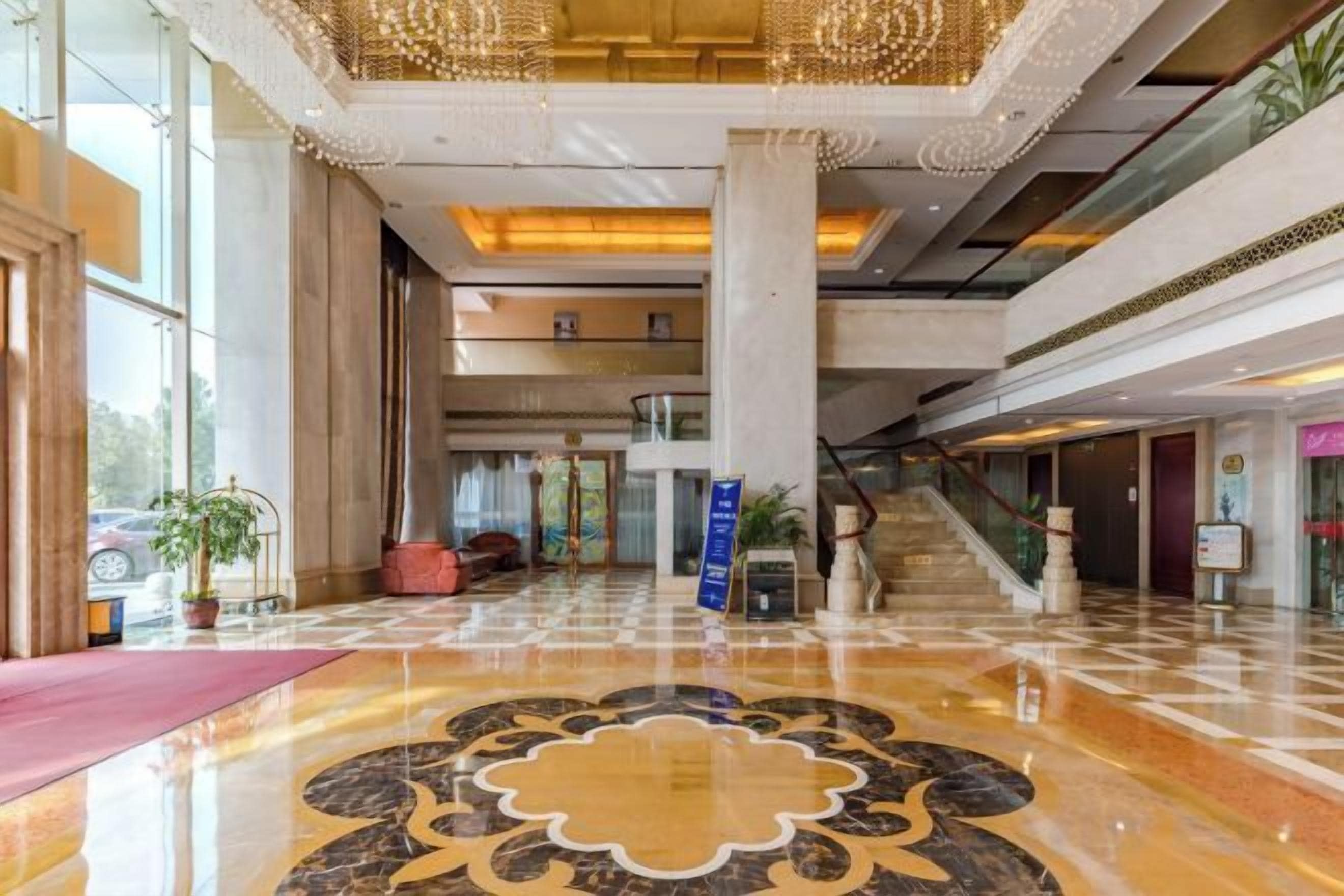 A spacious lobby with a marble floor, a staircase, and a reception desk.
