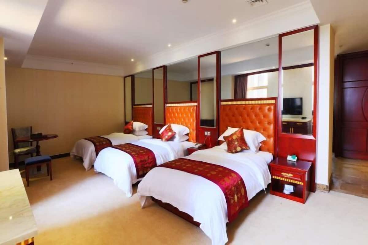A hotel room with two beds, a desk, a chair, a TV, and a large mirror.