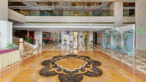 A spacious lobby with a grand chandelier, a central floral floor design, and a staircase leading to an upper level. - Fan Chang Hotel (Wuhu)