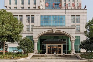 Un edificio de varios pisos con una entrada destacada, amplias ventanas y un letrero con caracteres chinos.