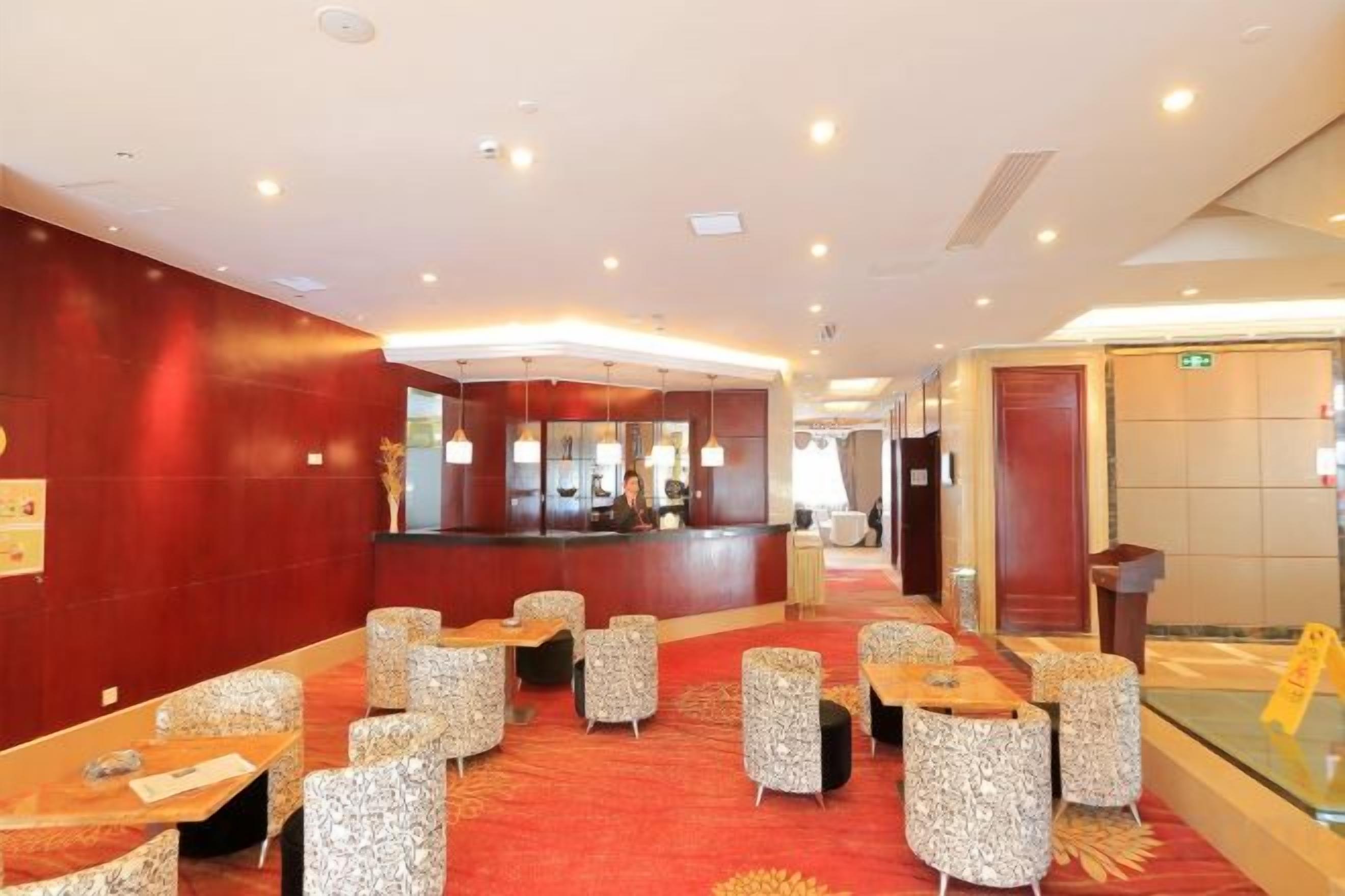 Un hall de hotel con mostrador de recepción, zona de estar y un panel de vidrio.