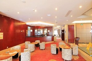 Un hall de hotel con mostrador de recepción, zona de estar y un panel de vidrio.