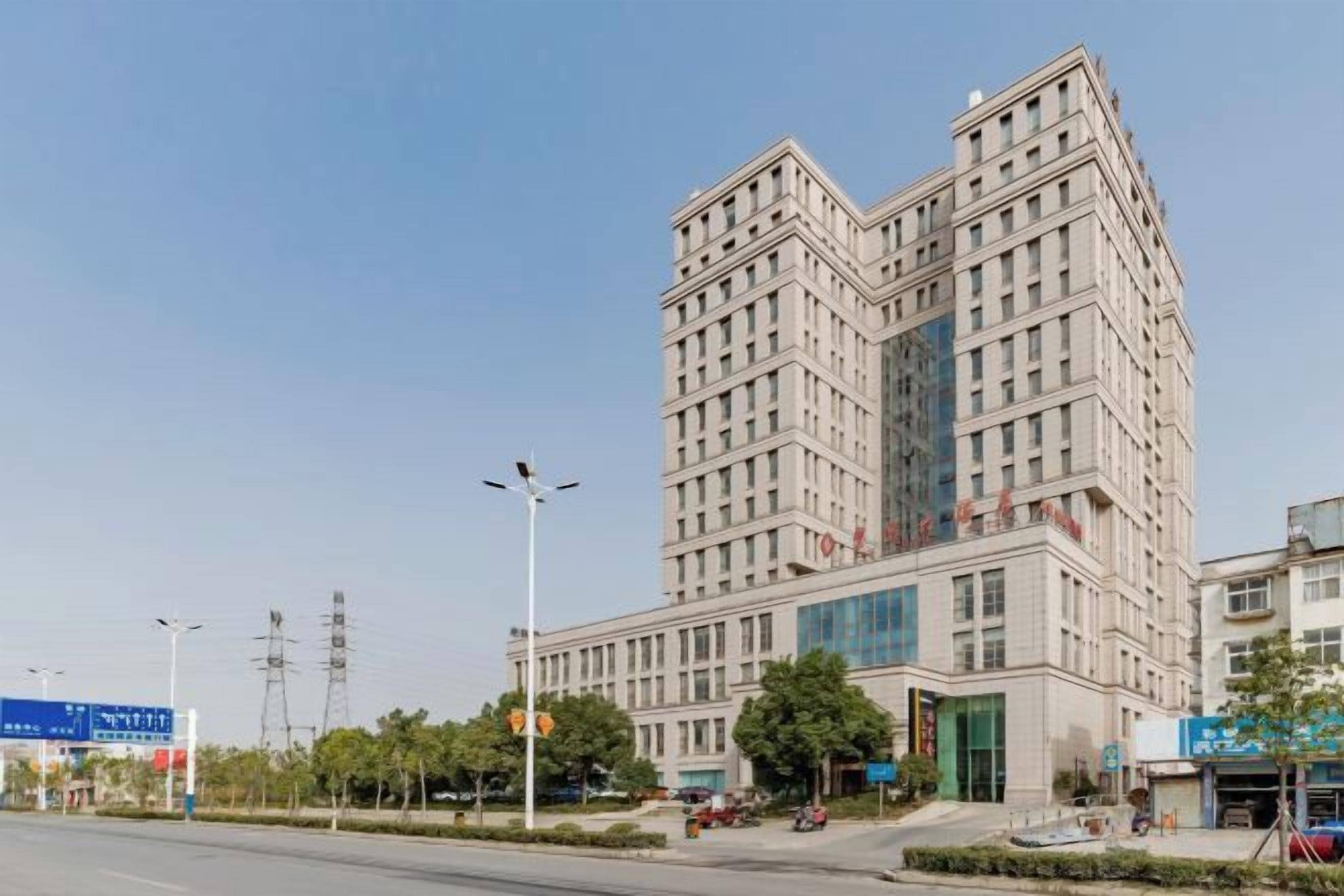 Un edificio de varios pisos con un diseño arquitectónico moderno, que destaca por una entrada principal y un amplio frente de cristal.