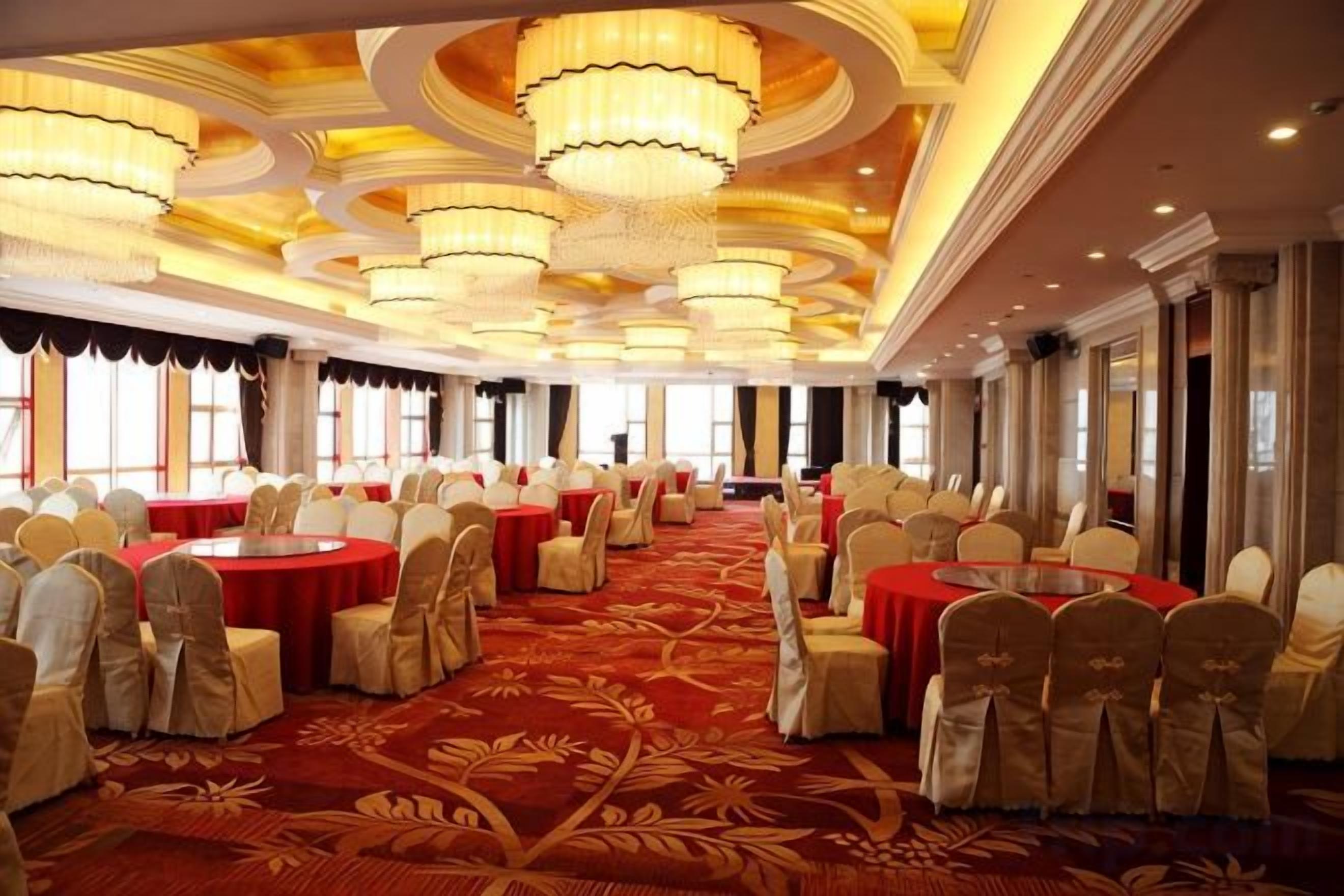Un salón de banquetes con mesas redondas, sillas y candelabros.